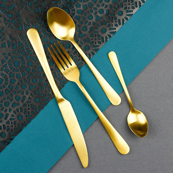 Four pieces of cutlery in gold coating on a blue tablecloth background
