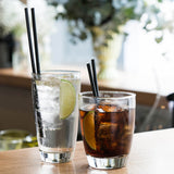 One large and one small tumblers with liquid against a restaurant background